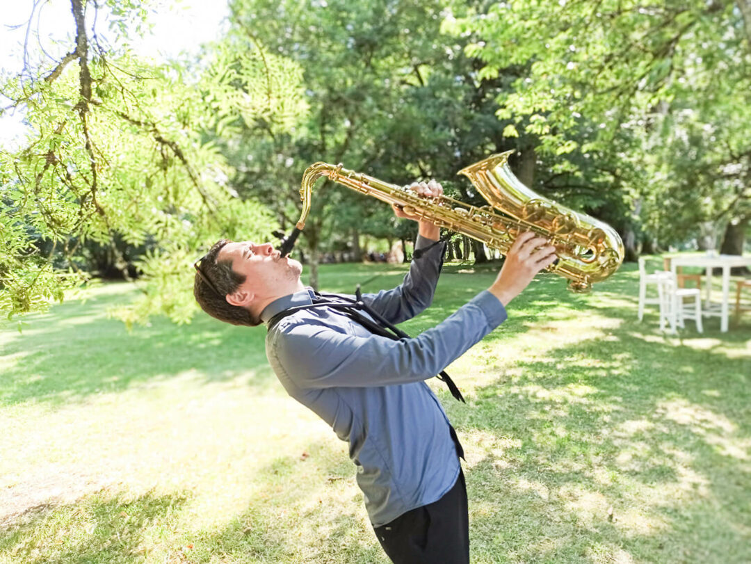 Saxophonist performing live during a wedding cocktail hour in a Provençal garden
