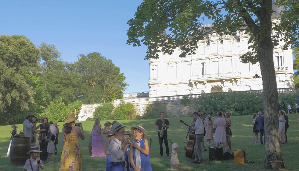 Jazz trio performing for wedding guests in the garden of a château