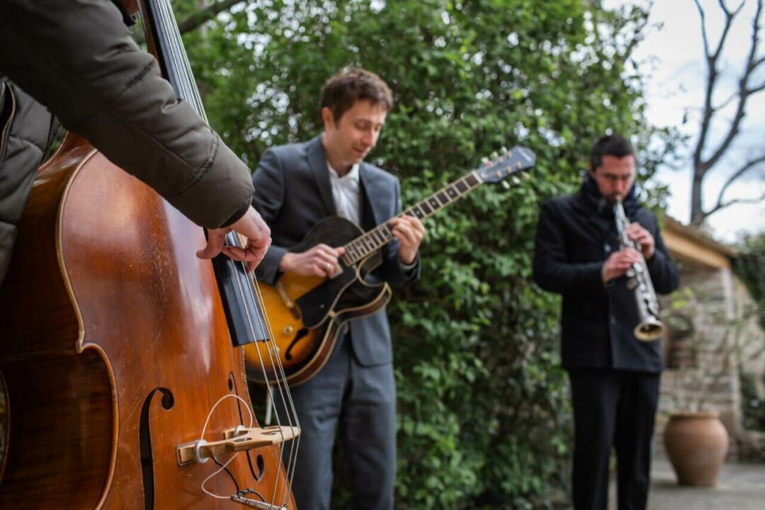 Jazz trio performing in front of a château during a wedding cocktail hour